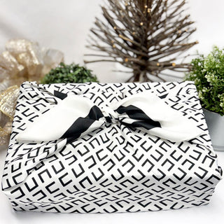 Gift wrapped in black and white patterned paper with a bow, set against a decorative background.