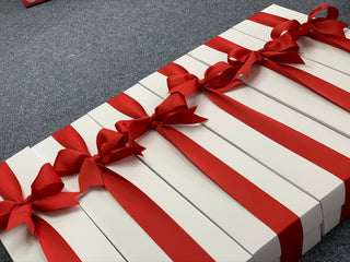 White gift box with red stripes and bows on a gray surface