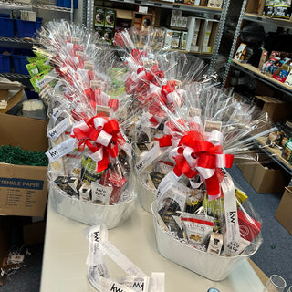 Row of gift baskets with red and white bows on a table in a store setting.