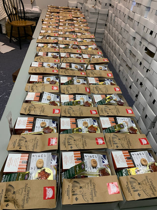 Table with numerous cardboard boxes containing gourmet gift baskets for a volume order
