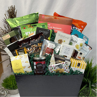 Gourmet gift basket with various food items on a neutral background before being packaged